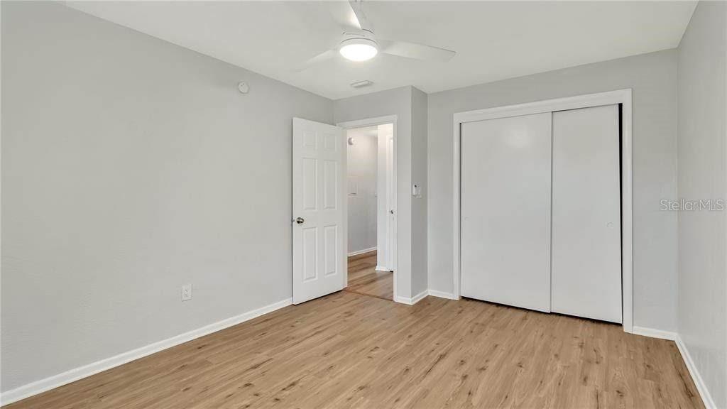 An empty bedroom features light gray walls, wood-look flooring, a ceiling fan, and sliding closet doors — 5900 22ND AVENUE N, ST PETERSBURG, FL