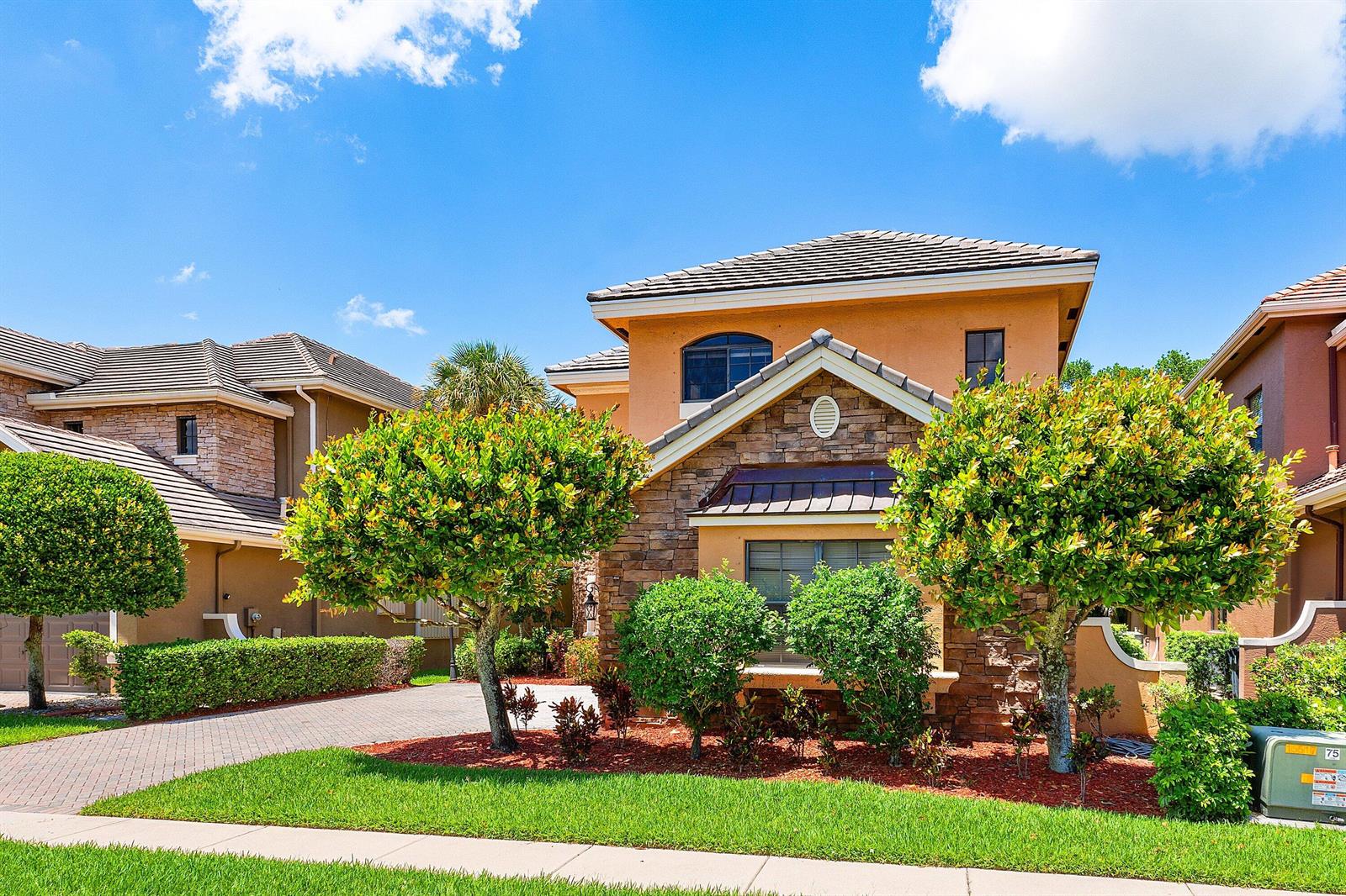 A two-story house with a stone facade, a tiled roof, and a paved driveway — 10293 Medicis Place, Wellington FL 33449, WELLINGTON, FL