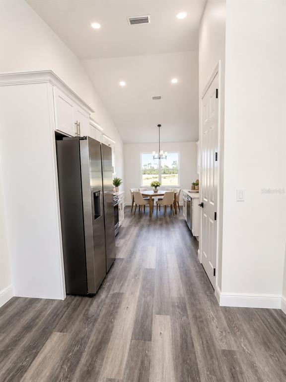 A kitchen with stainless steel appliances and white cabinets leads to a dining area — 9483 SW 121ST TERRACE, DUNNELLON, FL