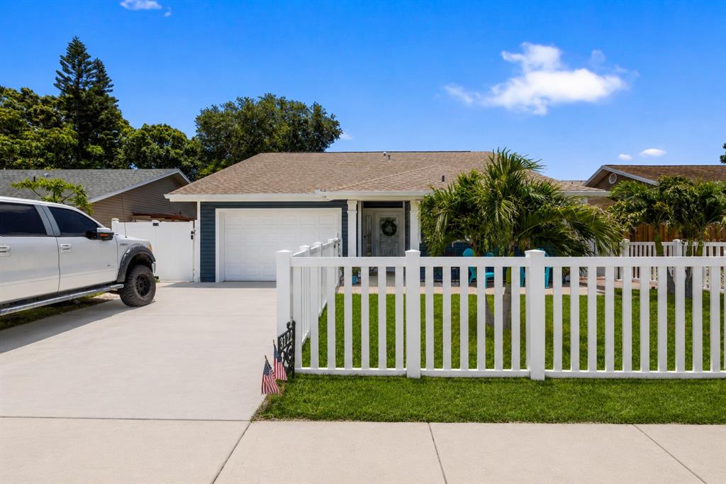 A single-story house with a white fence, a concrete driveway, and a white pickup truck — 3122 WHISPERING DRIVE N, LARGO, FL