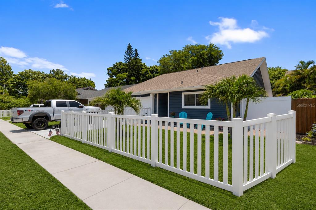 A blue house with a white picket fence and a silver pickup truck parked outside — 3122 WHISPERING DRIVE N, LARGO, FL