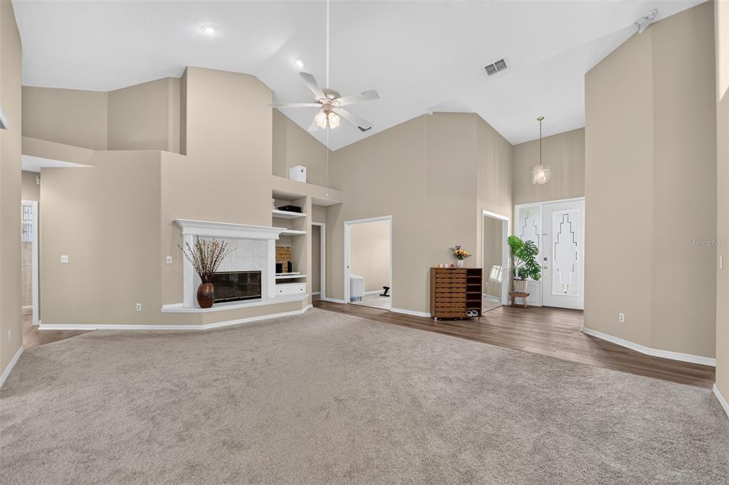 A living room with beige carpet, a fireplace, built-in shelves, and a vaulted ceiling — 804 ROSEMIST COURT, OCOEE, FL