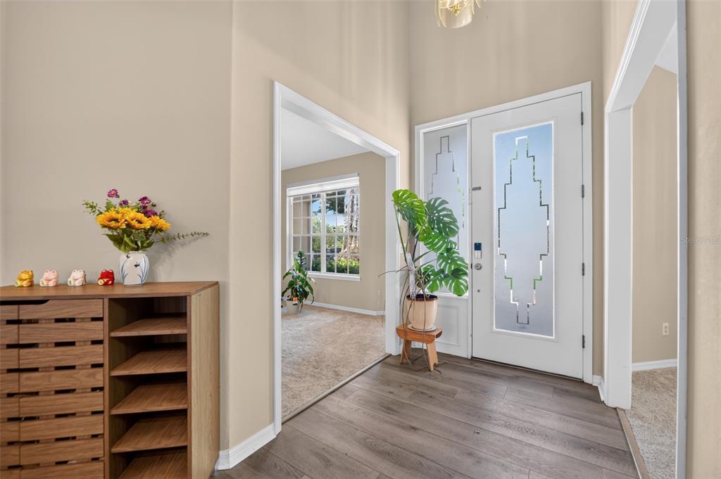 An entryway with wood-look flooring, a white front door, and a wooden shoe cabinet — 804 ROSEMIST COURT, OCOEE, FL