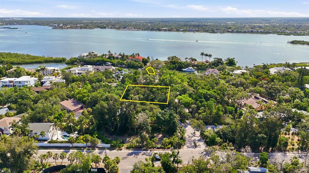 An aerial view shows a rectangular vacant lot outlined in yellow amidst a wooded neighborhood — 1325 HIDDEN HARBOR WAY, SARASOTA, FL