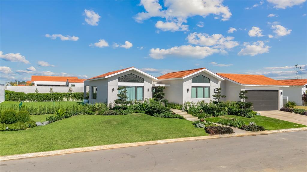A modern, single-story house with a tiled roof, large windows, and a manicured front lawn — 765 CAMINO DE LOS ANTURIOS, DORADO, PR