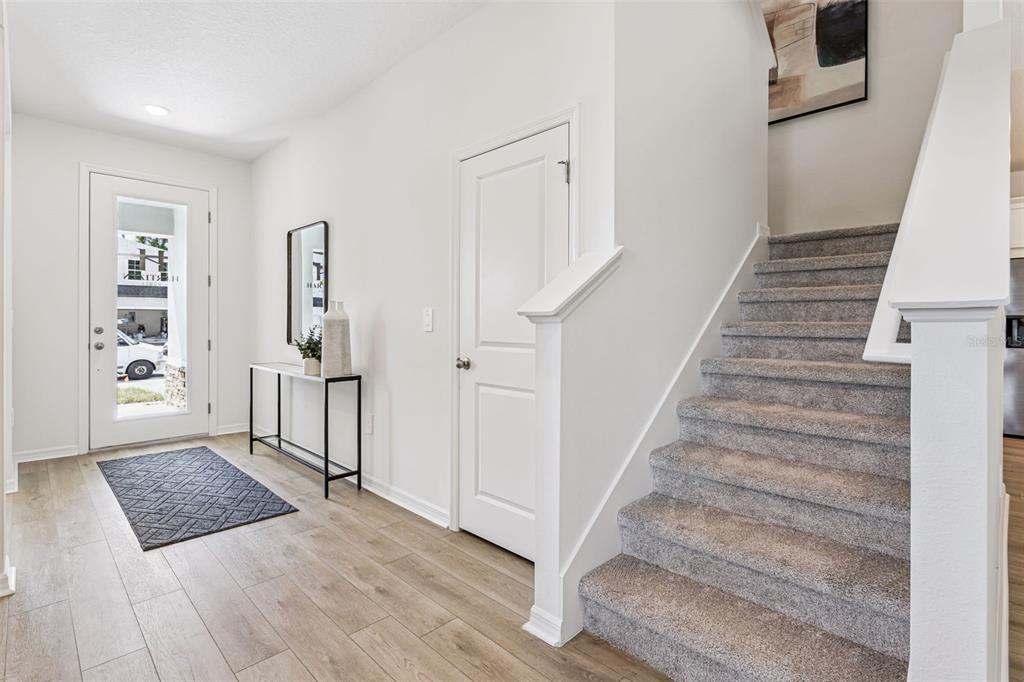 An entryway features wood-look flooring, a carpeted staircase, a white door, and a console table — 4271 DARBY COURT, EUSTIS, FL