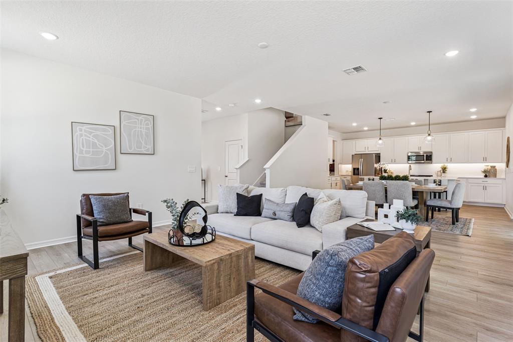 A living room with a sofa and two leather chairs sits before an open kitchen — 4271 DARBY COURT, EUSTIS, FL