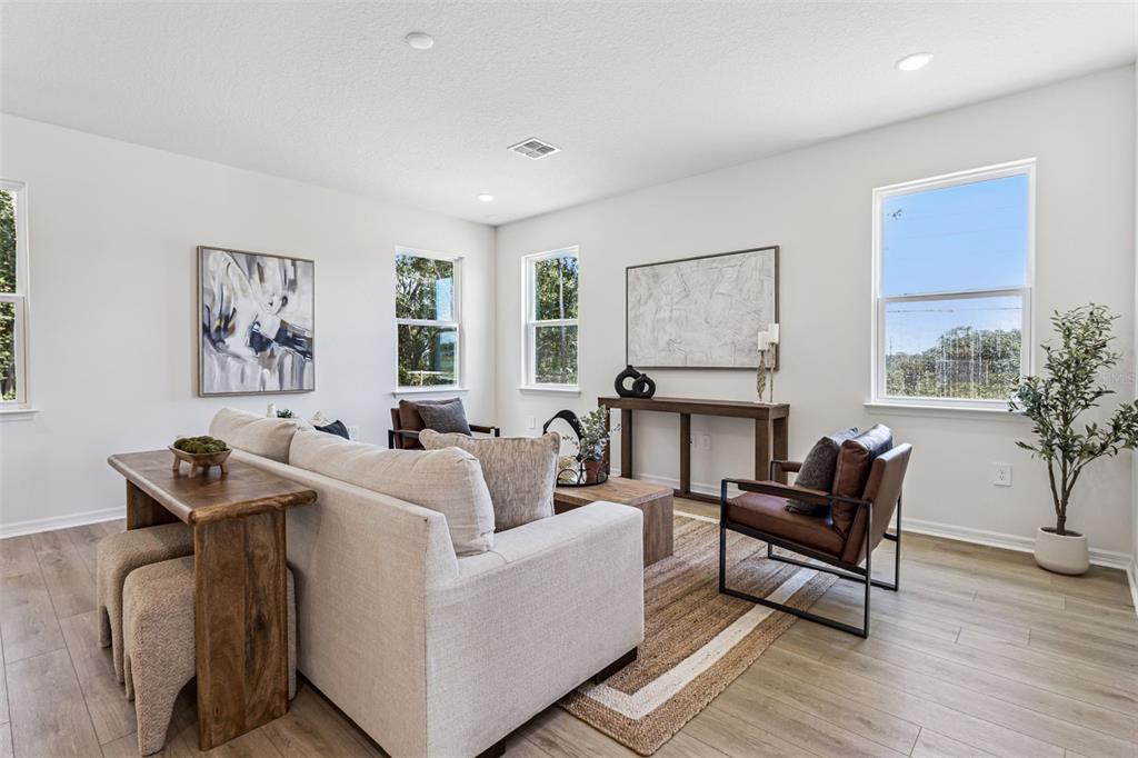 A living room features a light-colored sofa, two leather chairs, and wood-toned flooring — 4271 DARBY COURT, EUSTIS, FL