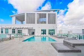 A rooftop swimming pool with lounge chairs on a paved deck against a blue sky — 133 NE 2nd Ave # 3410, Miami FL 33132, MIAMI, FL