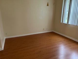 An empty room features light-colored walls, wood-look flooring, and vertical blinds on the window — 6211 Arlington Way, Fort Pierce FL 34951, FORT PIERCE, FL