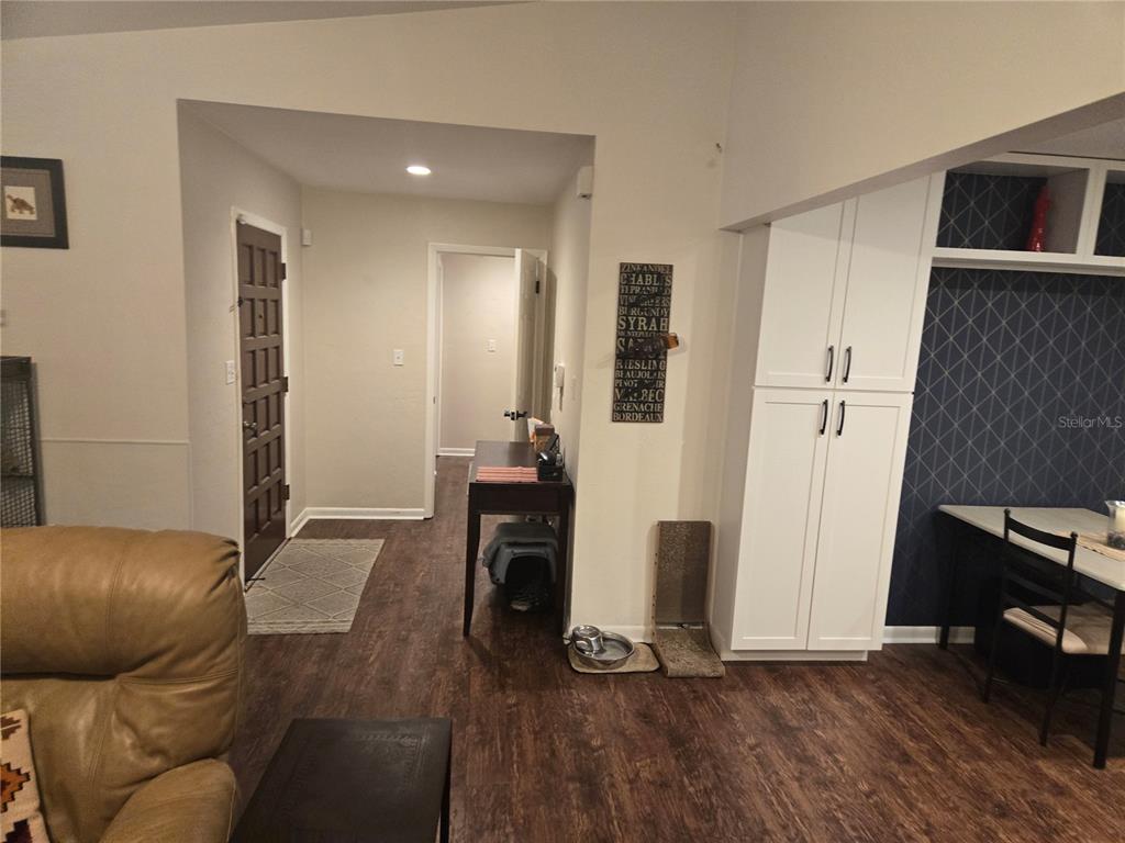 A living area features wood-look flooring, a dark front door, white cabinets, and a dining table — 7605 SW 7TH PLACE, GAINESVILLE, FL