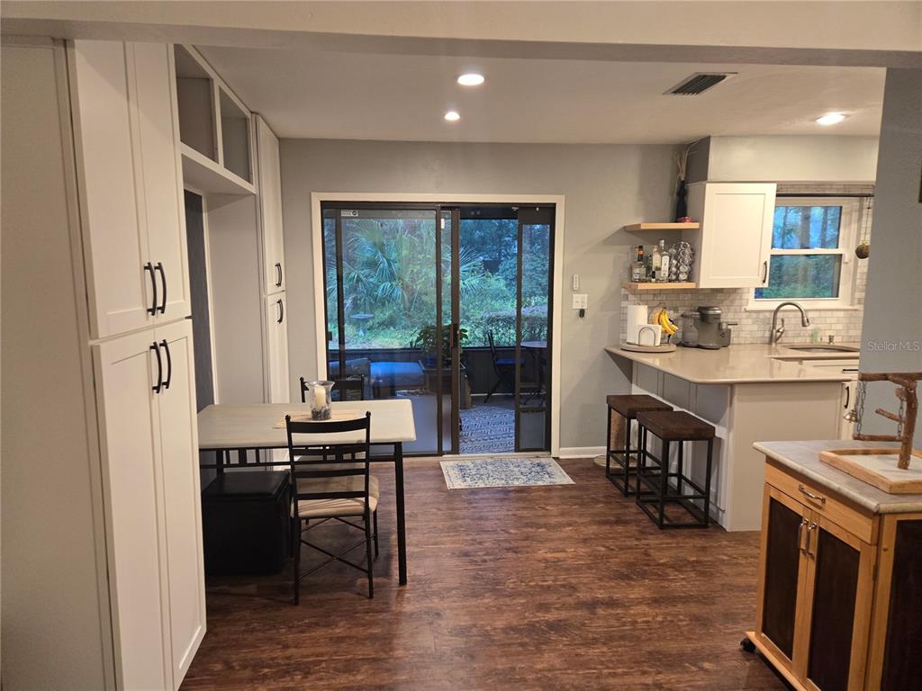 A kitchen with white cabinetry, a dining table, a breakfast bar, and sliding glass doors — 7605 SW 7TH PLACE, GAINESVILLE, FL