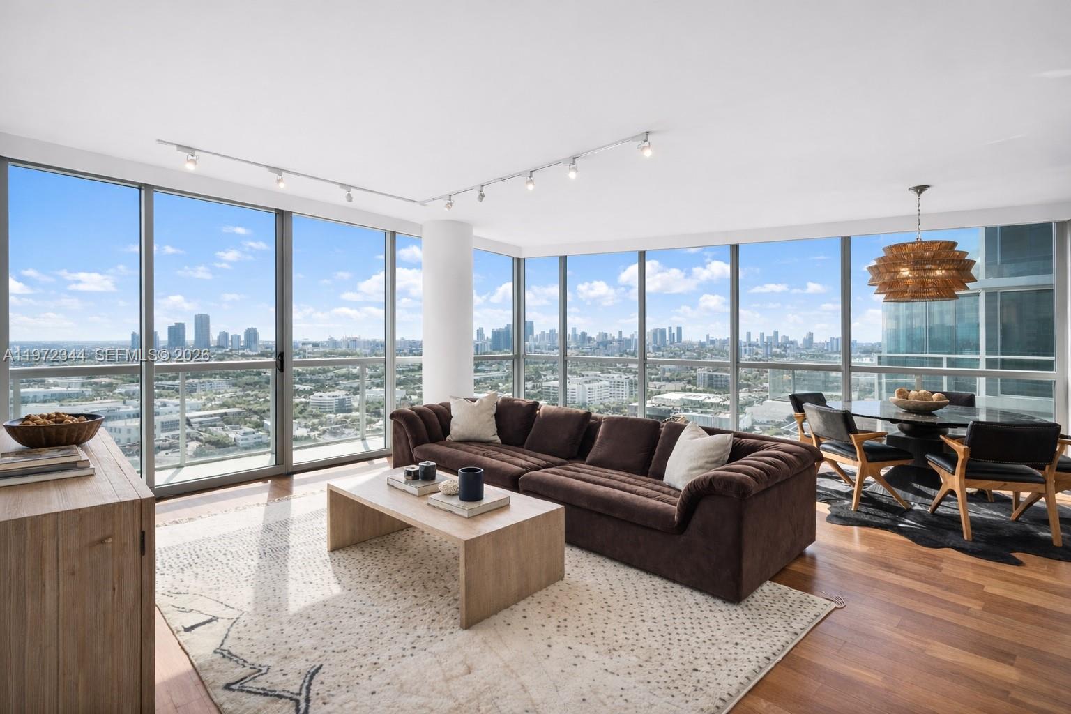 A living and dining area features floor-to-ceiling windows, a brown sofa, and city views — 101 20th St # 2706, Miami Beach FL 33139, MIAMI BEACH, FL