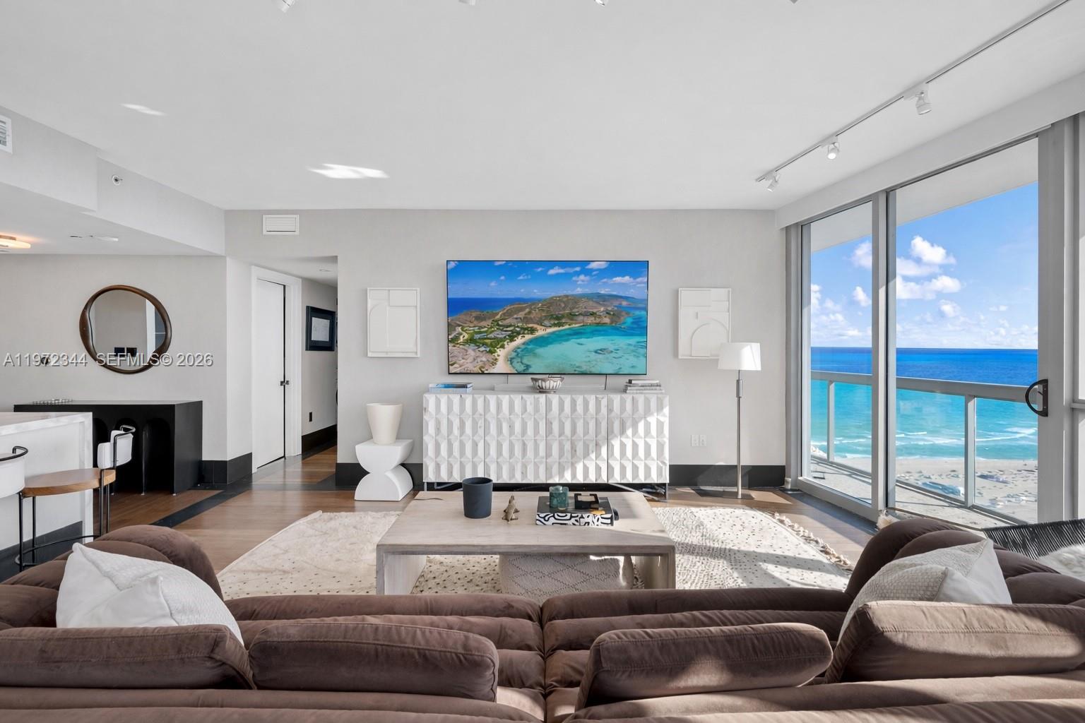 A living room features a brown sectional sofa, a white sideboard, and floor-to-ceiling ocean views — 101 20th St # 2706, Miami Beach FL 33139, MIAMI BEACH, FL