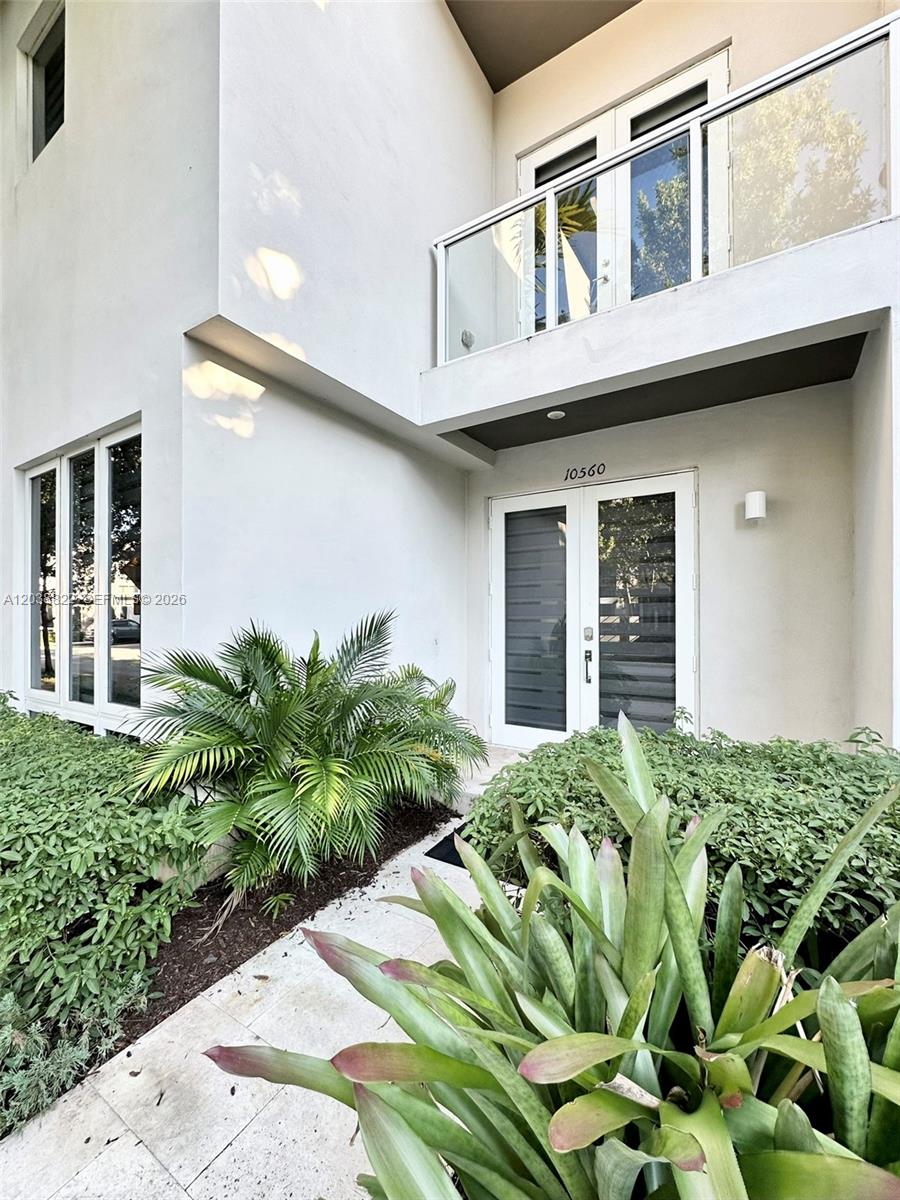 A modern white two-story building exterior features a glass-paneled balcony and a double-door entrance — 10560 NW 63rd Ter, Doral FL 33178, DORAL, FL