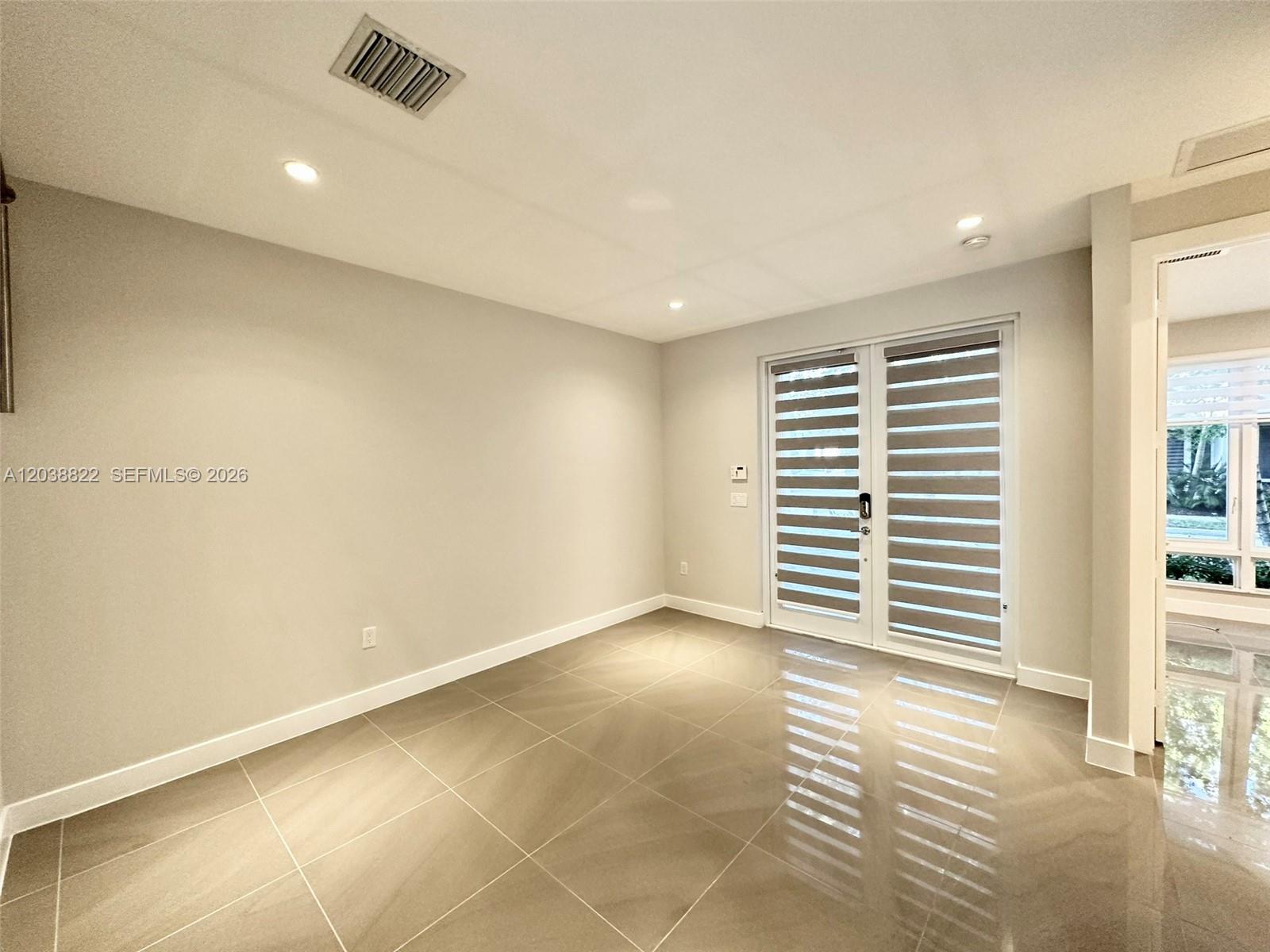 A room with light gray walls, large beige floor tiles, and glass-paned double doors — 10560 NW 63rd Ter, Doral FL 33178, DORAL, FL