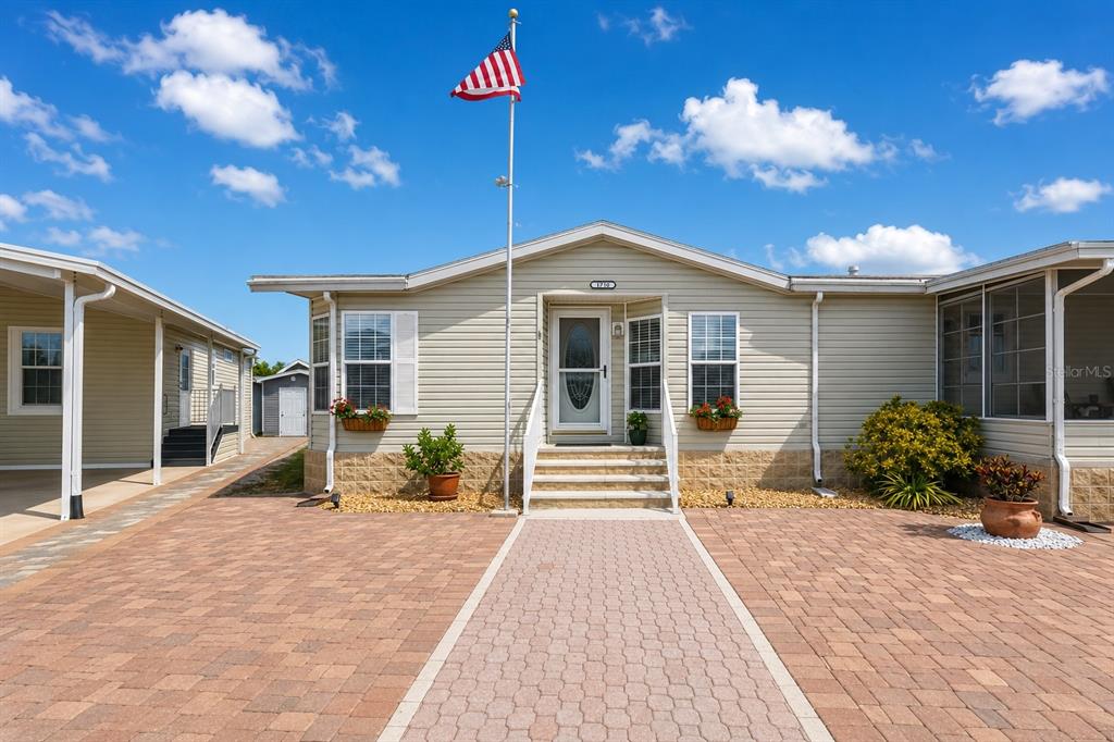 A single-story house with light siding, a brick paver driveway, and an American flag pole — 1710 INDIANA AVENUE, BRADENTON, FL