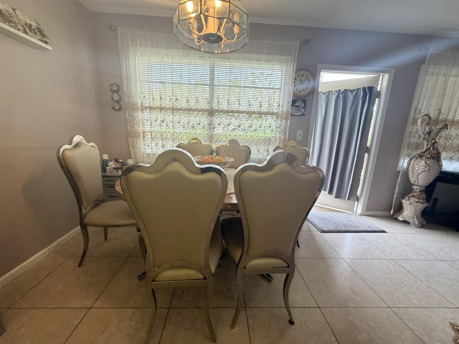 A dining room features a marble-topped table, six upholstered chairs, and tile flooring — 1011 Ventnor Crescent, Deerfield Beach FL 33442, DEERFIELD BEACH, FL