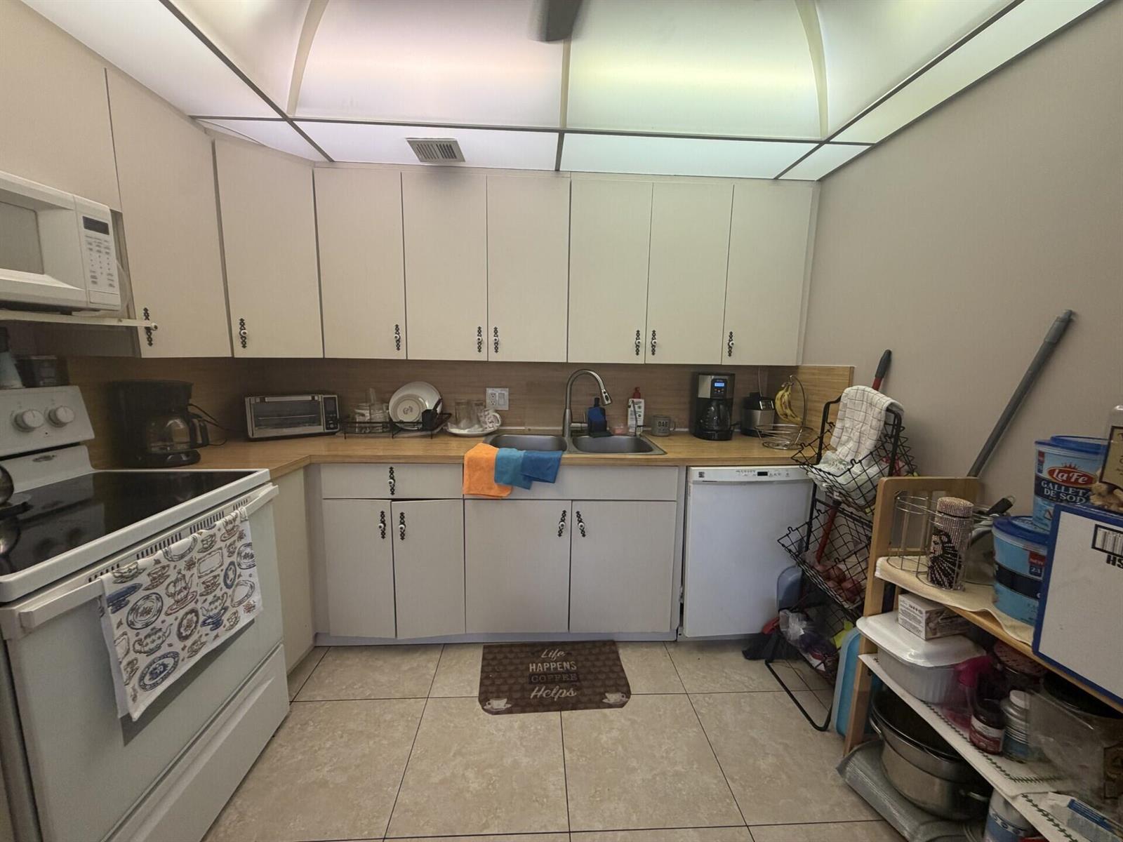 A kitchen features white cabinets, light wood countertops, a double sink, and white appliances — 1011 Ventnor Crescent, Deerfield Beach FL 33442, DEERFIELD BEACH, FL