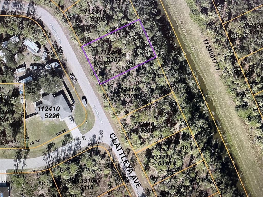 This is an aerial map showing a vacant, wooded residential lot outlined in purple — LOT 7 CLATTLEYA AVENUE, NORTH PORT, FL