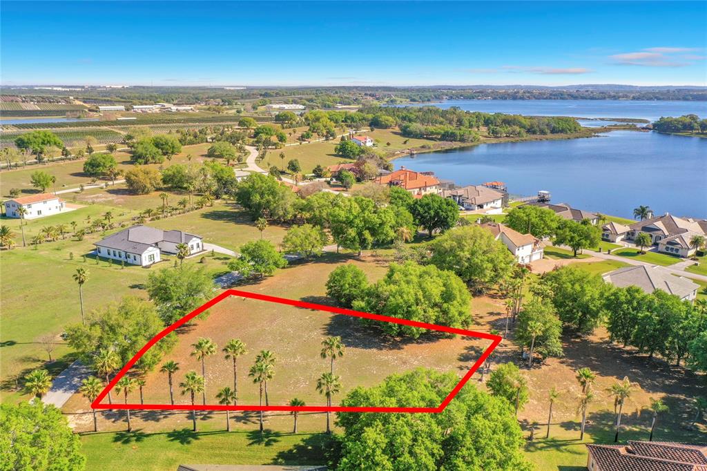 An aerial view shows a vacant, rectangular plot of land outlined in red near a lake — MARIGOLD STREET, GROVELAND, FL