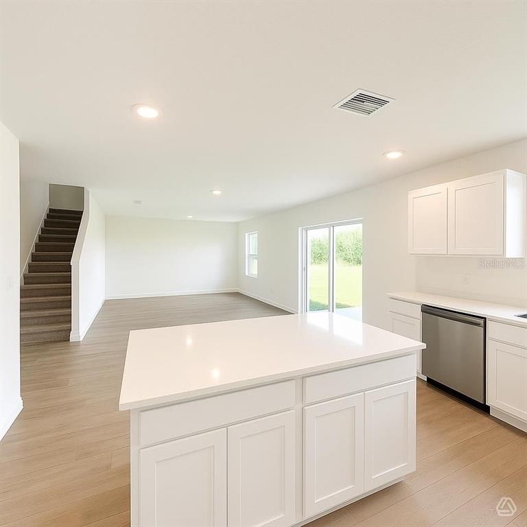 A kitchen with a white island and cabinets overlooks an open living area with stairs — 13213 SASSAFRAS TRAIL, PARRISH, FL