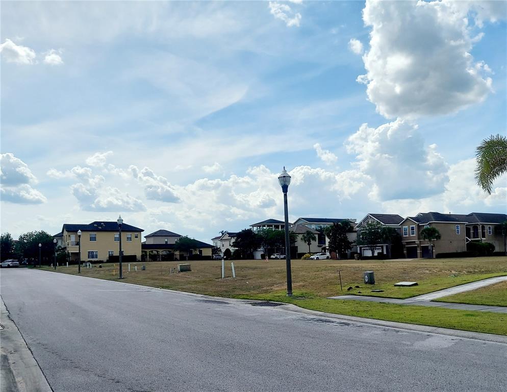 A vacant residential lot sits between suburban houses along a paved street — 7813 LOXAHATCHEE COURT, REUNION, FL
