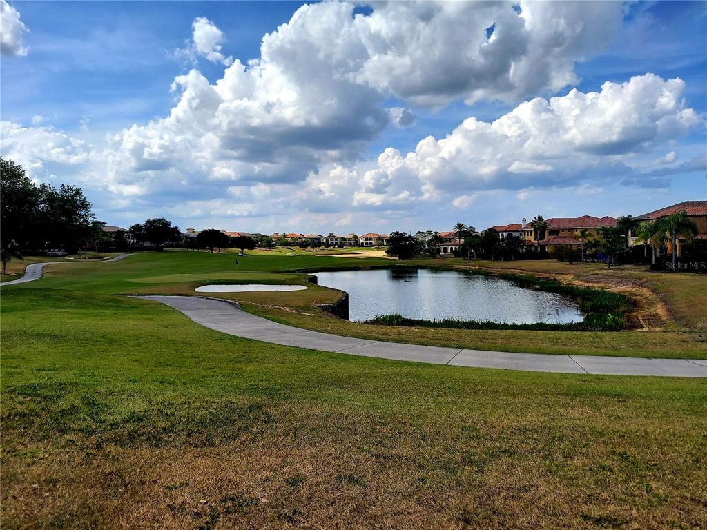 A golf course view featuring a pond, a sand bunker, and residential homes in the background — 7813 LOXAHATCHEE COURT, REUNION, FL