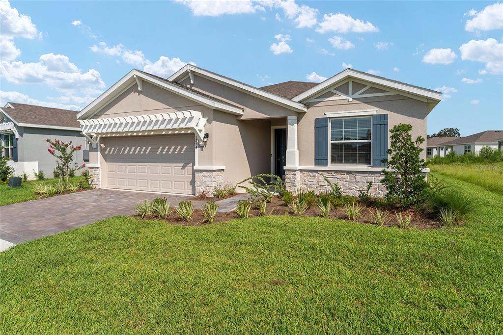 A single-story house with a beige stucco exterior, stone accents, and a white wooden pergola — 5254 NW 43RD LANE ROAD, OCALA, FL