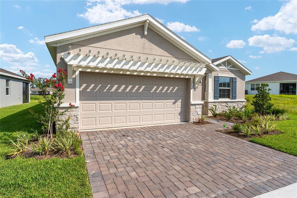 A single-story house exterior features a two-car garage, a pergola, and a paver driveway — 5254 NW 43RD LANE ROAD, OCALA, FL