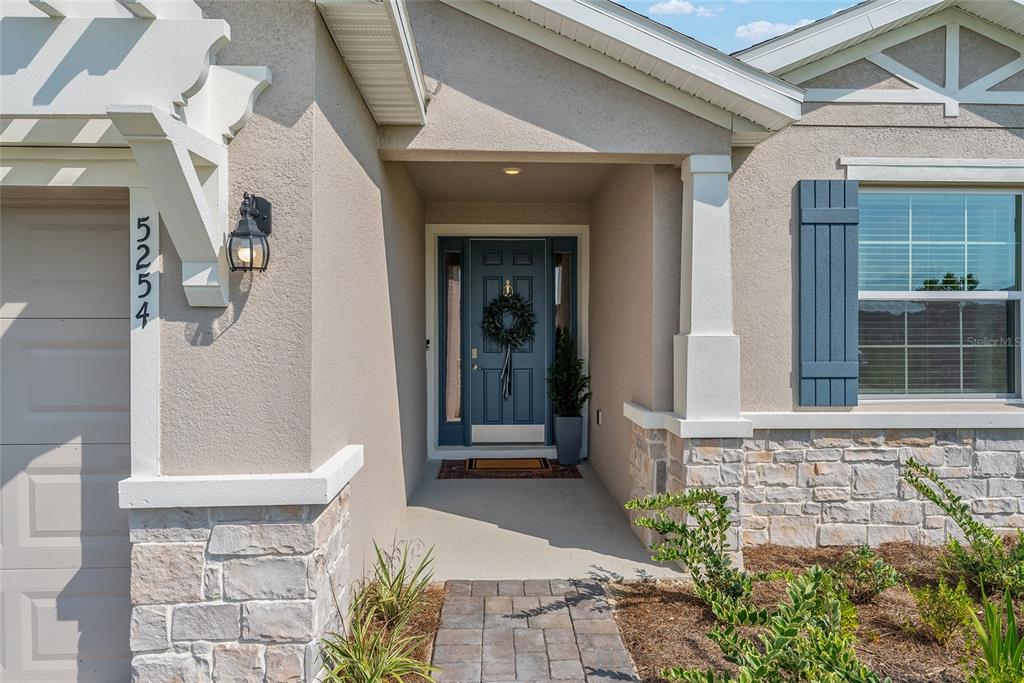 The exterior of a house features a blue front door, stone siding, and a walkway — 5254 NW 43RD LANE ROAD, OCALA, FL