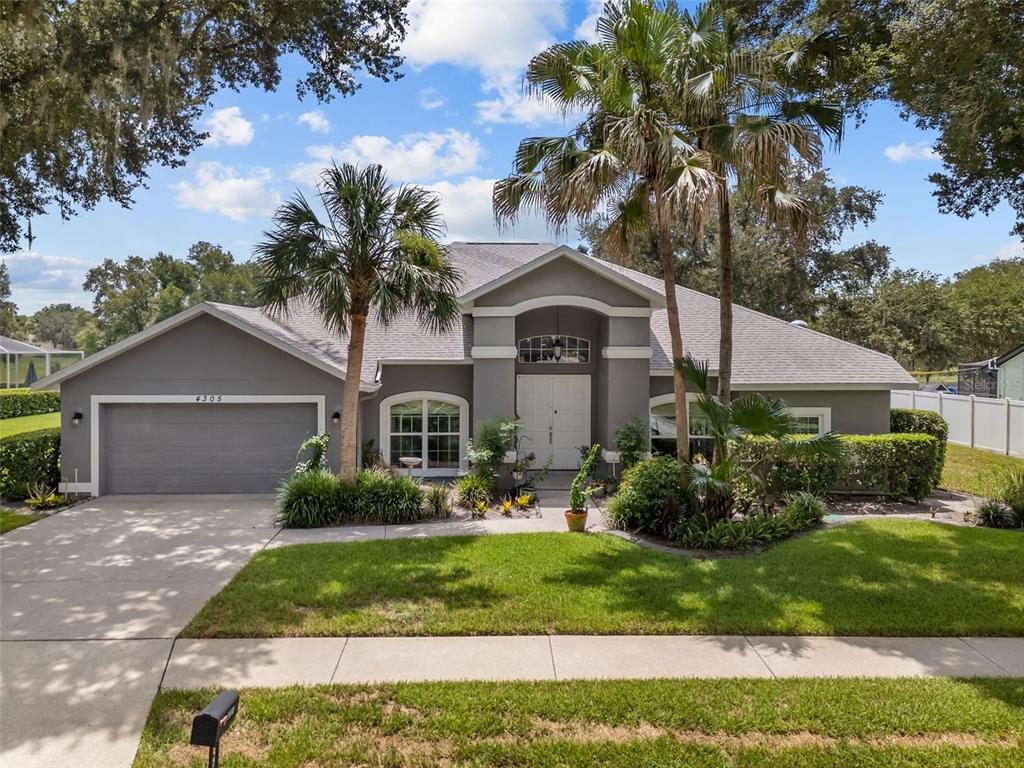 A single-story gray house with a two-car garage, arched windows, and palm trees in front — 4305 GENTRICE DRIVE, VALRICO, FL