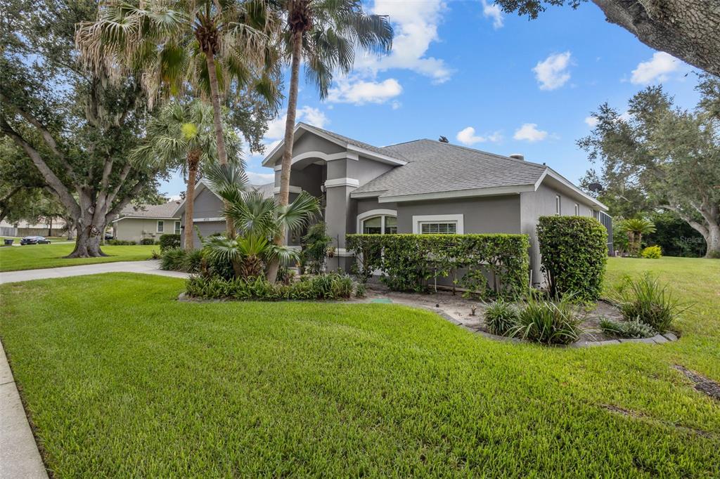 A gray single-story house with a palm tree, manicured hedges, and a green lawn — 4305 GENTRICE DRIVE, VALRICO, FL