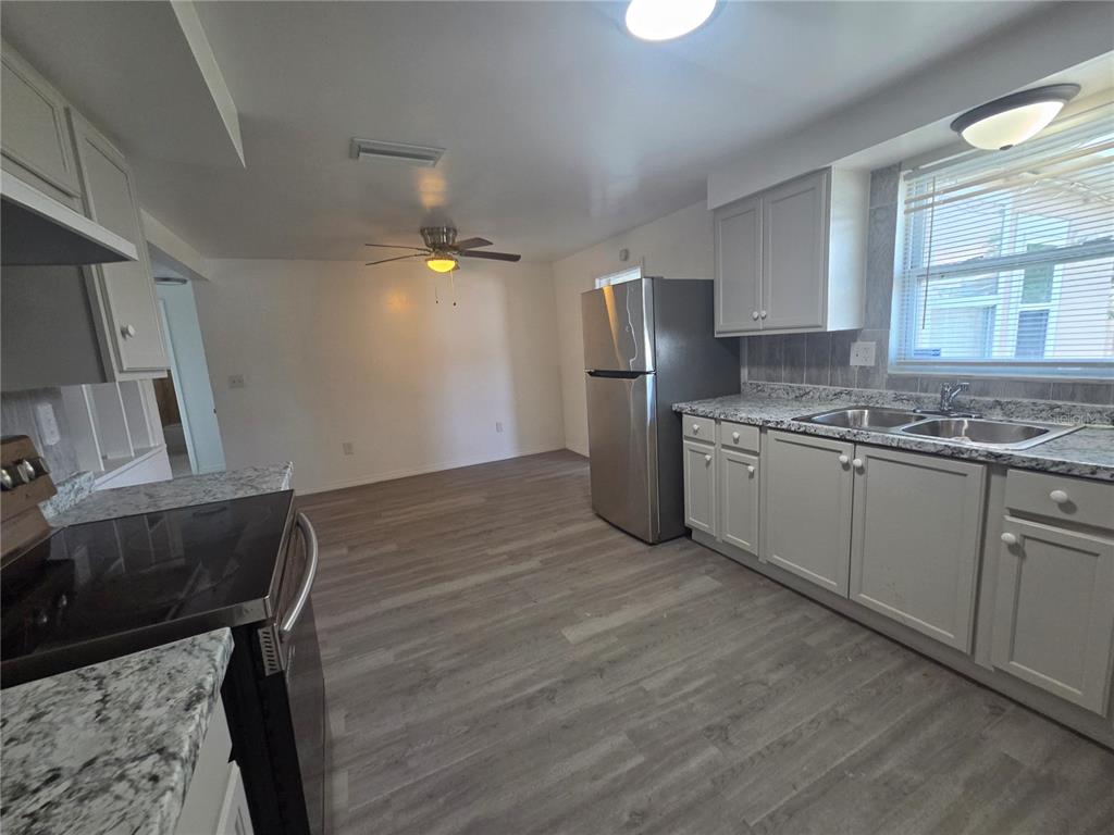 A kitchen features gray cabinets, granite countertops, stainless steel appliances, and wood-look flooring — 1731 DANDER DRIVE, HOLIDAY, FL
