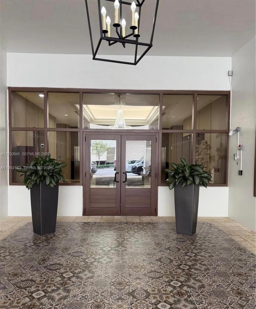 A building entrance features double glass doors, two large potted plants, and patterned floor tiles — 357 Almeria Ave # 802, Coral Gables FL 33134, CORAL GABLES, FL