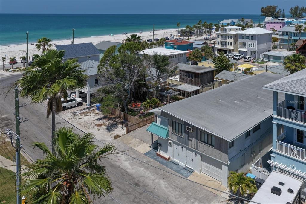 An elevated view shows a coastal neighborhood with houses, palm trees, and a sandy beach — 40 77TH AVENUE, TREASURE ISLAND, FL
