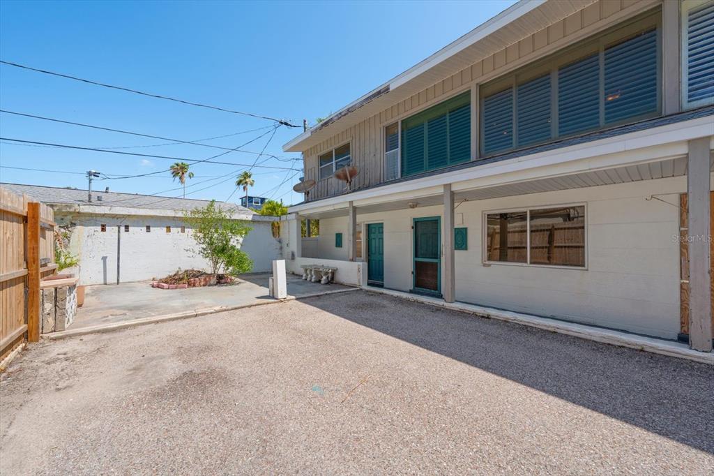 A two-story building exterior with a gravel parking area and a small garden bed — 40 77TH AVENUE, TREASURE ISLAND, FL