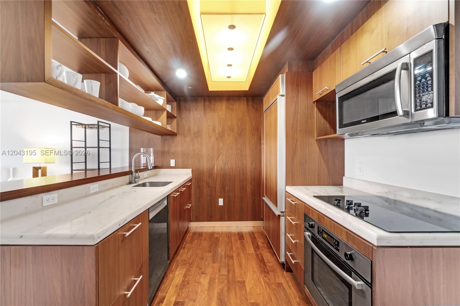 A galley kitchen features wood cabinetry, marble countertops, and a recessed ceiling light fixture — 50 Biscayne Blvd # 904, Miami FL 33132, MIAMI, FL