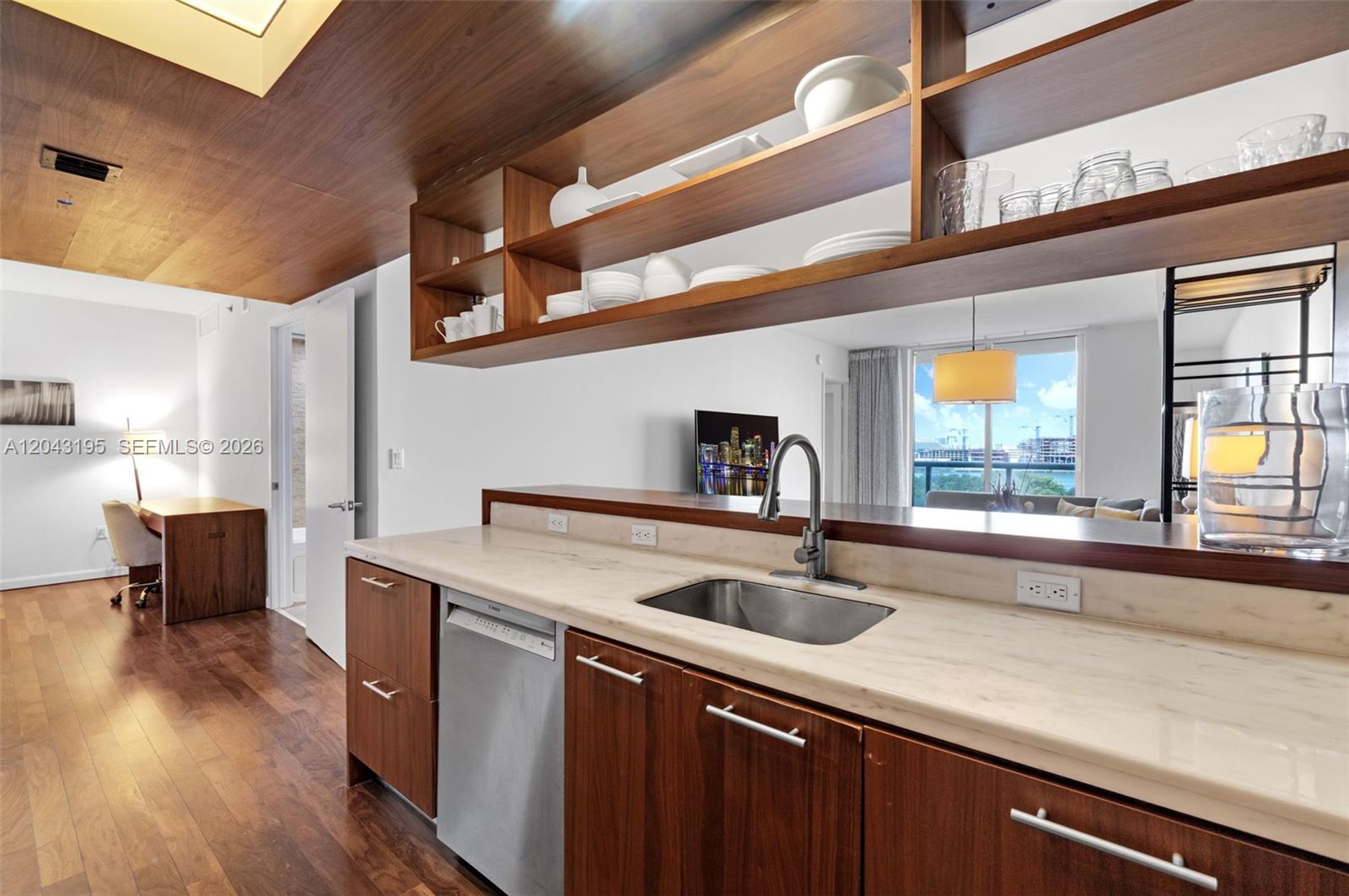 A kitchen features wood cabinetry, open shelving, a stainless steel sink, and light stone countertops — 50 Biscayne Blvd # 904, Miami FL 33132, MIAMI, FL