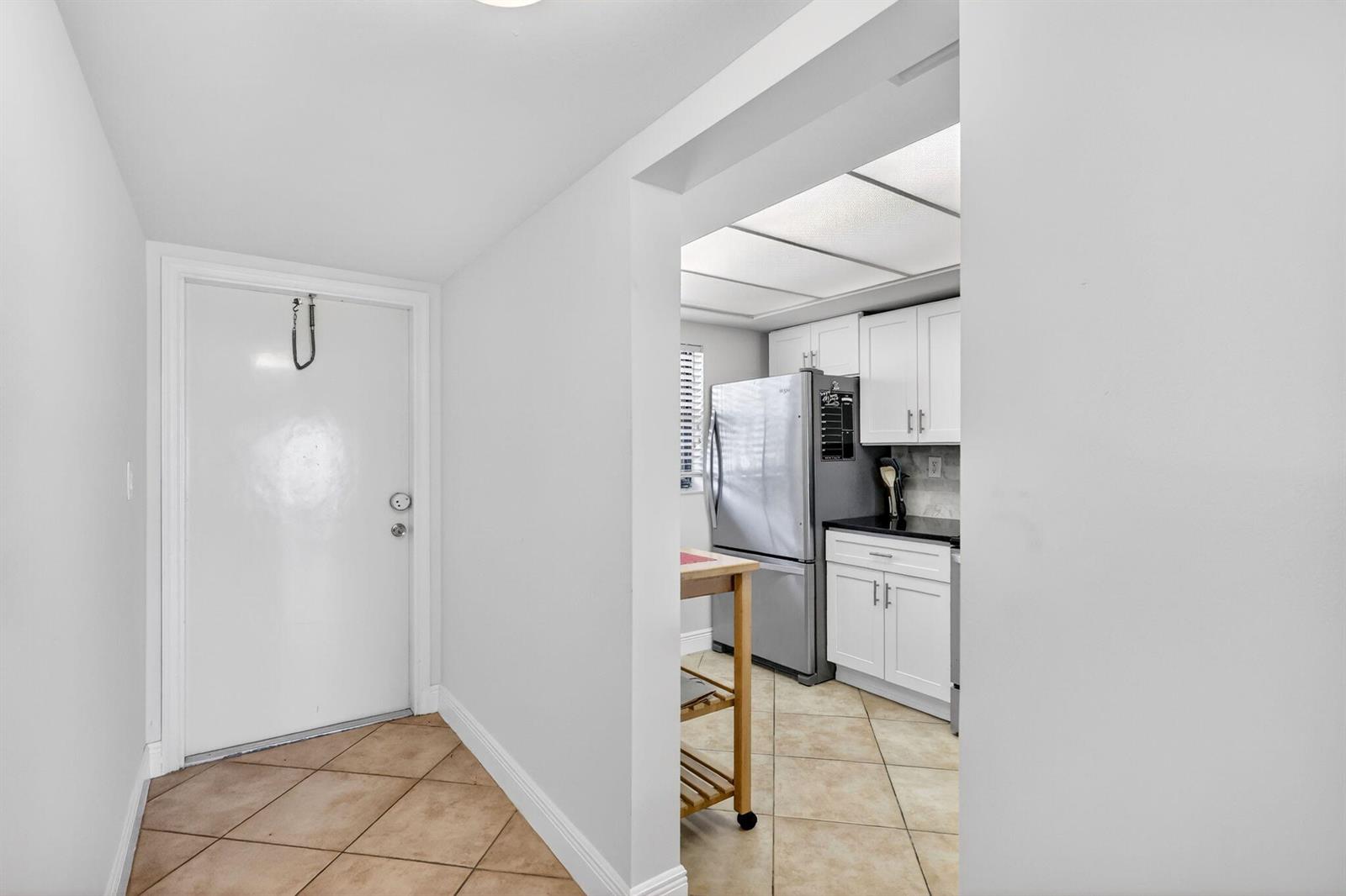 A tiled entryway leads into a kitchen featuring white cabinets and stainless steel appliances — 10310 S Ocean Drive # 107, Jensen Beach FL 34957, JENSEN BEACH, FL