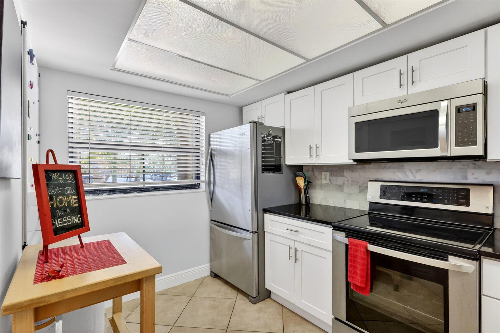 A kitchen with white cabinets, stainless steel appliances, black countertops, and a small wooden table — 10310 S Ocean Drive # 107, Jensen Beach FL 34957, JENSEN BEACH, FL