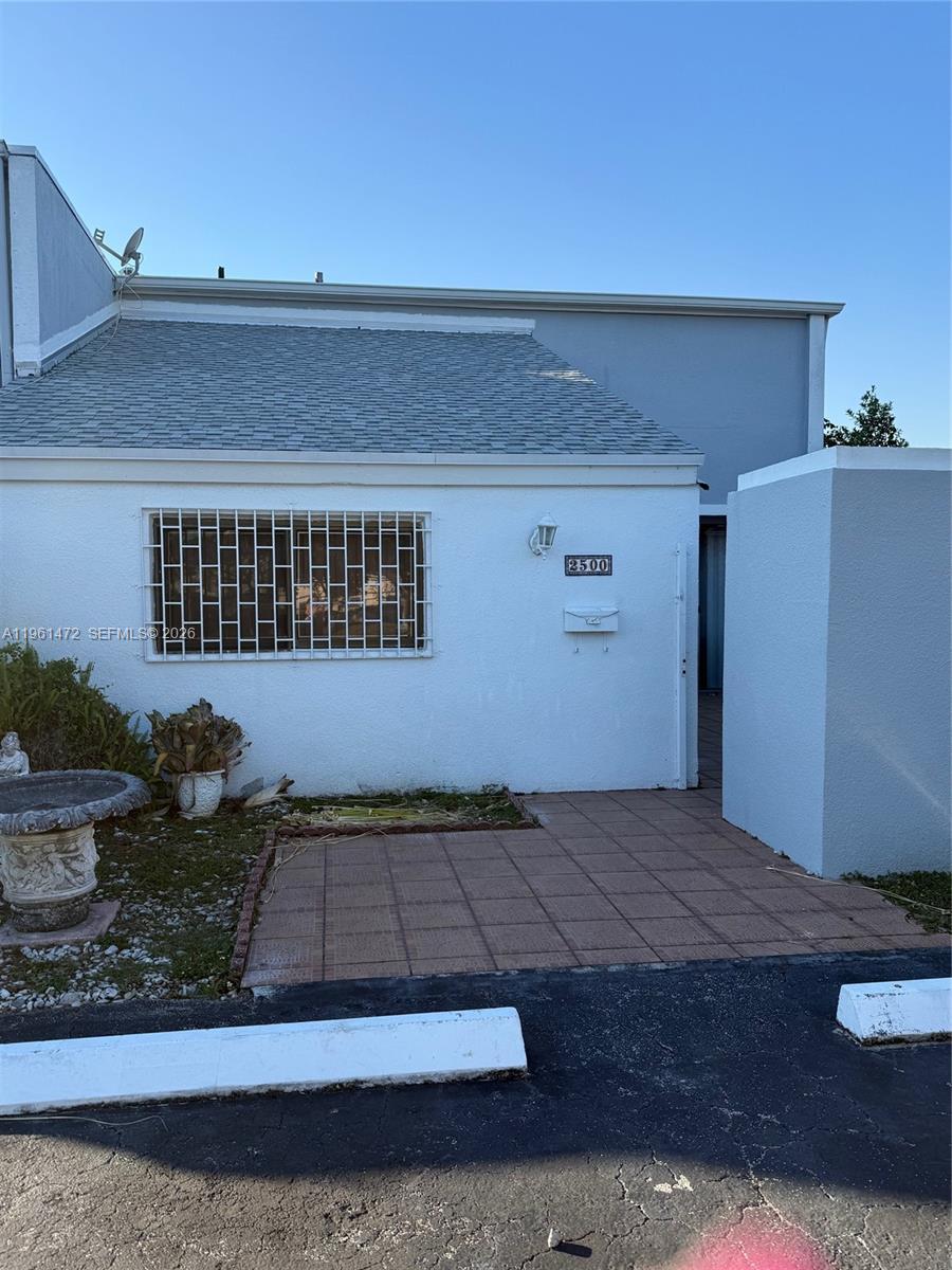 The exterior view shows a white stucco building with a tiled patio and security bars — 2500 SW 122nd Ct, Miami FL 33175, MIAMI, FL