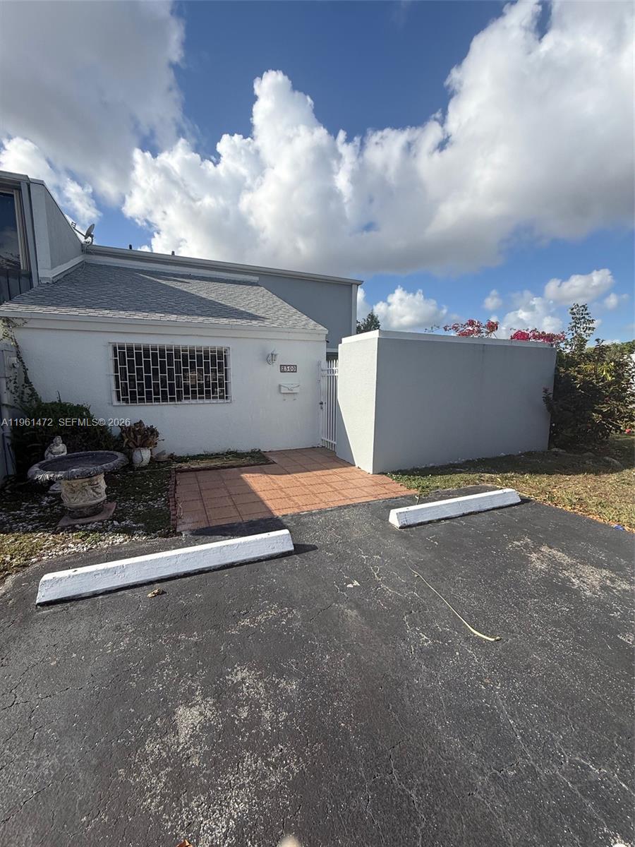 A white exterior home features a tiled entryway, a security-barred window, and a parking space — 2500 SW 122nd Ct, Miami FL 33175, MIAMI, FL