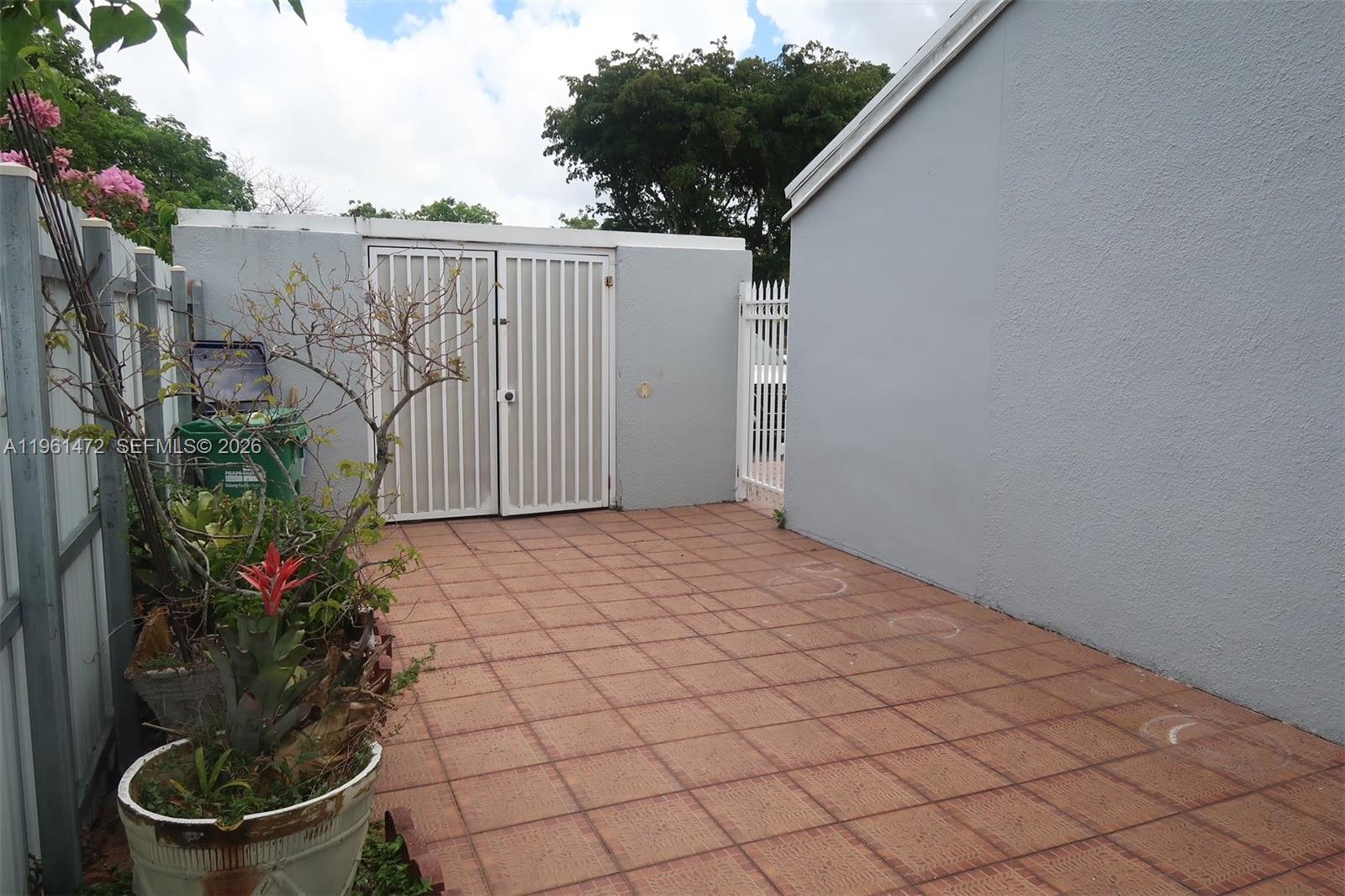 A paved patio area features a storage shed with white doors and a white fence — 2500 SW 122nd Ct, Miami FL 33175, MIAMI, FL