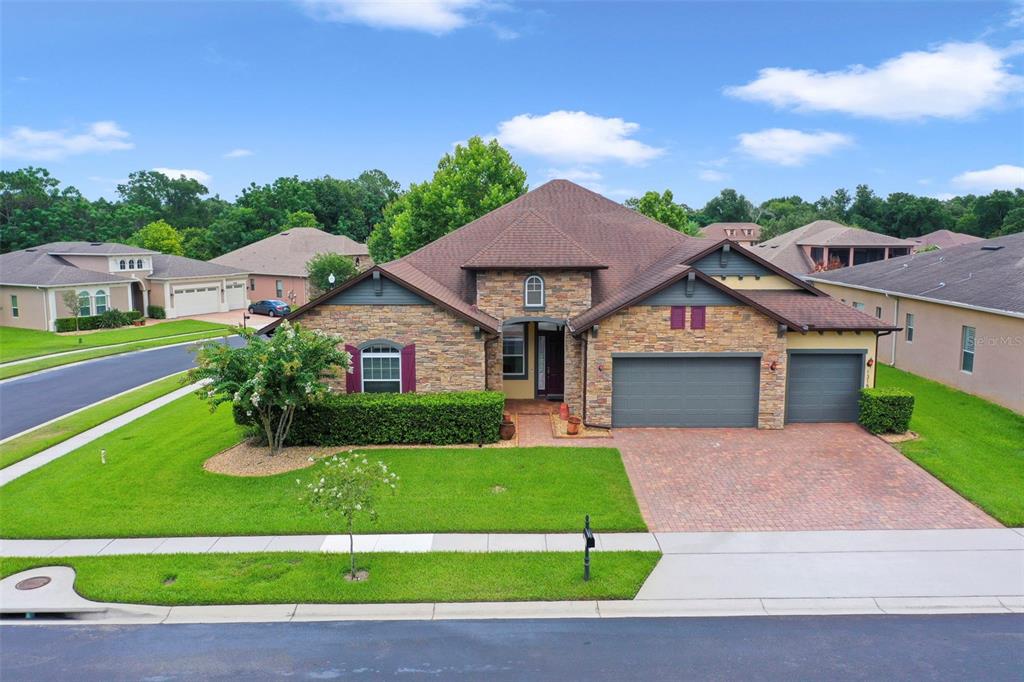 A single-story house with a stone facade, a brick driveway, and a three-car garage — 1315 ARDEN OAKS DRIVE, OCOEE, FL