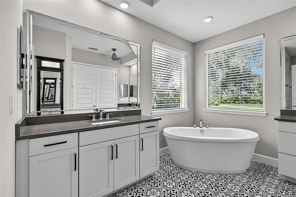 A bathroom features a gray vanity with a dark countertop, a soaking tub, and patterned flooring — 38 NEW LEATHERWOOD DRIVE, PALM COAST, FL