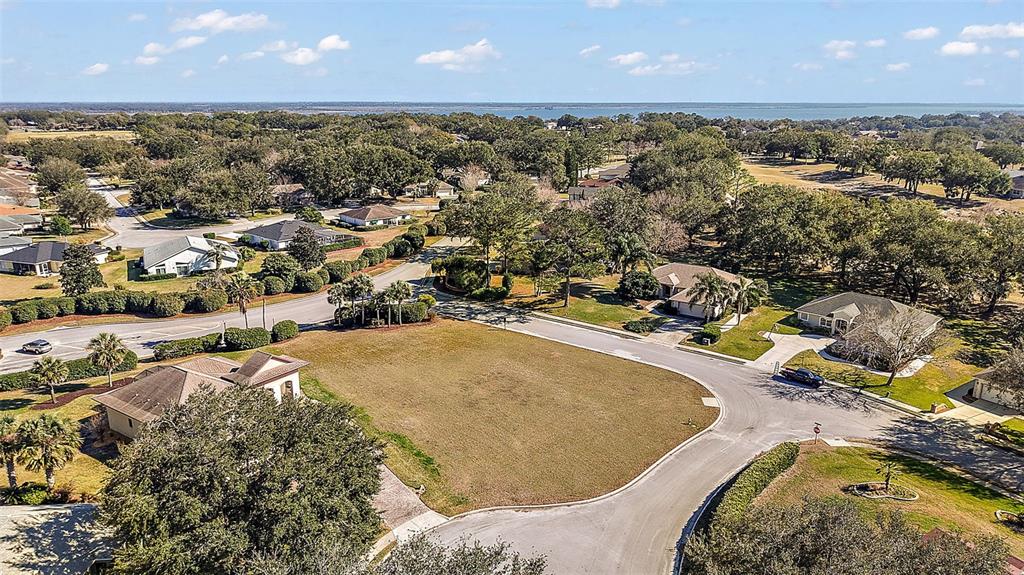An aerial view shows a vacant residential lot surrounded by suburban houses and mature trees — 5049 HARBOR HEIGHTS, LADY LAKE, FL