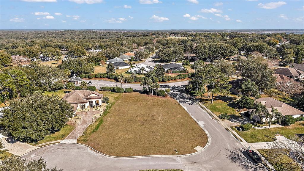 An aerial view shows a vacant residential lot situated between two houses on a cul-de-sac — 5049 HARBOR HEIGHTS, LADY LAKE, FL