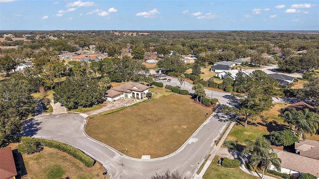An aerial view shows a vacant residential lot situated on a corner in a neighborhood — 5049 HARBOR HEIGHTS, LADY LAKE, FL