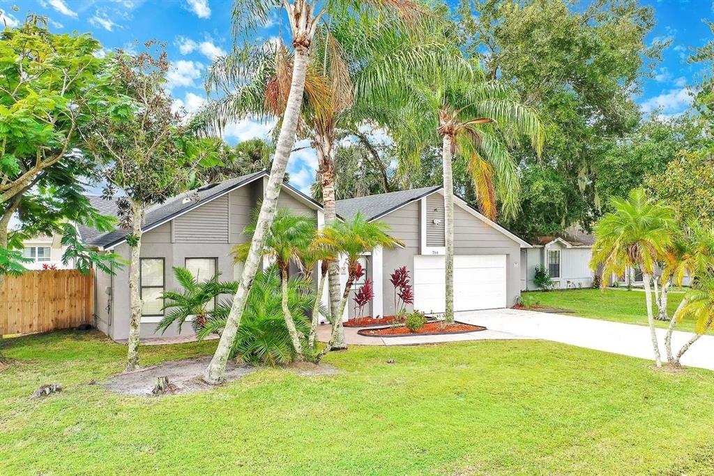 A single-story gray house with a two-car garage and palm trees in the front yard — 714 CARIBOU DRIVE, POINCIANA, FL